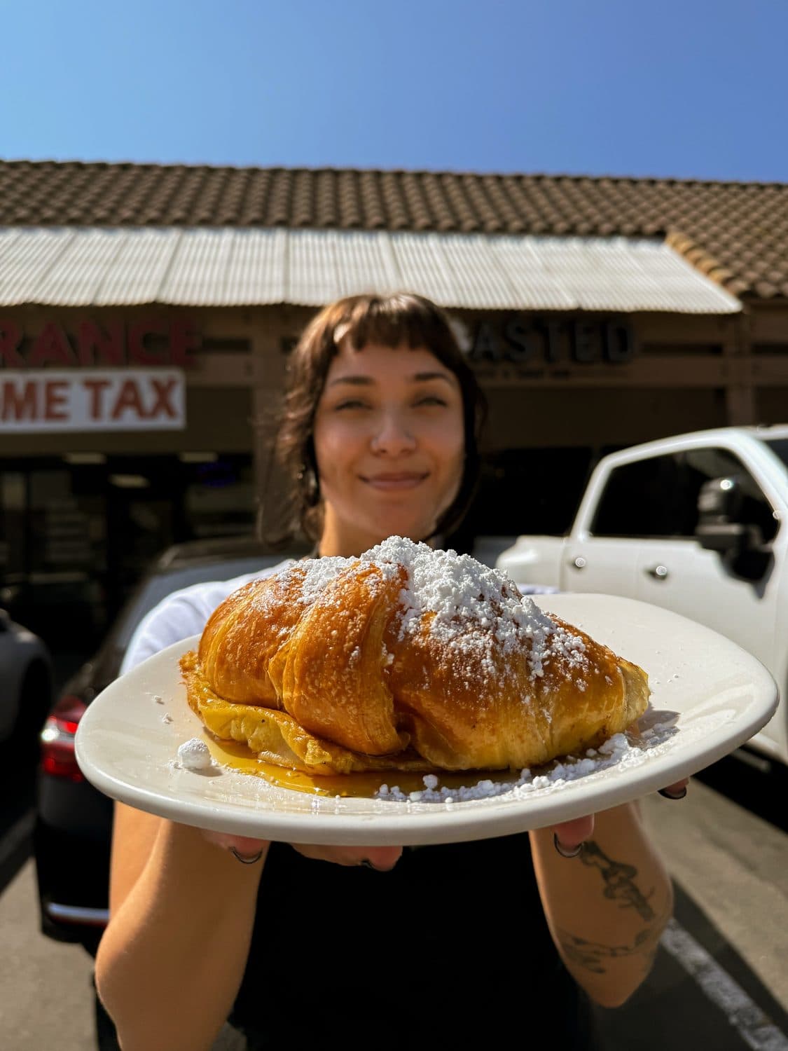 A TOASTED team member with a fresh plate outside the Arlington Ave shop